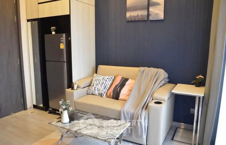 Modern living room with stylish decor and compact design, featuring a cozy sofa and sleek refrigerator.