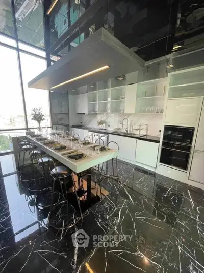 Luxurious modern kitchen with sleek design and high-end appliances, featuring marble flooring and large windows.