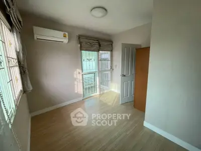 Bright empty bedroom with wooden flooring and air conditioning