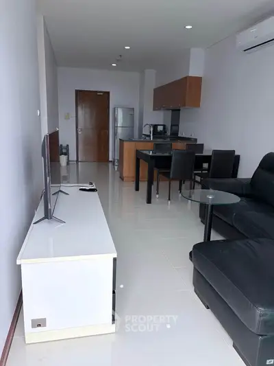 Modern open-plan living room with sleek kitchen and stylish furnishings in a contemporary apartment.