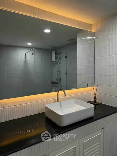 Modern bathroom with sleek sink and illuminated mirror in stylish apartment.