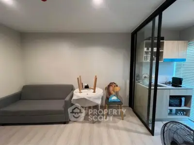 Modern living room with gray sofa and compact kitchen in open layout apartment.