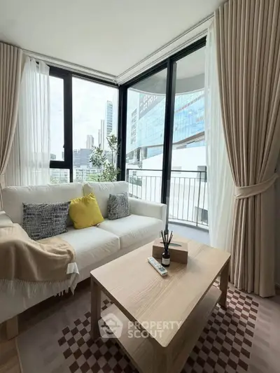 Modern living room with large windows and city view, featuring stylish decor and cozy seating area.