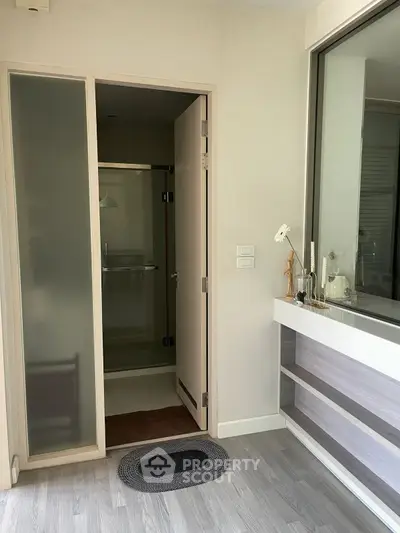 Modern bathroom entrance with frosted glass door and sleek interior design.