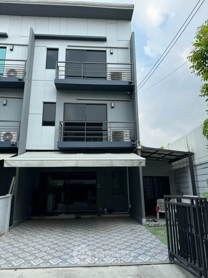 Modern three-story townhouse with sleek design and spacious driveway in a serene neighborhood.