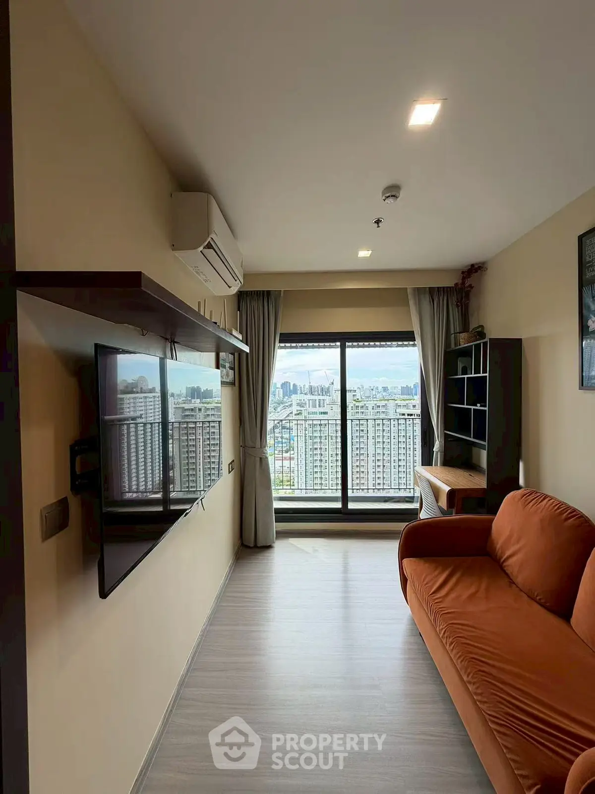 Modern living room with city view, featuring sleek furniture and large window for natural light.