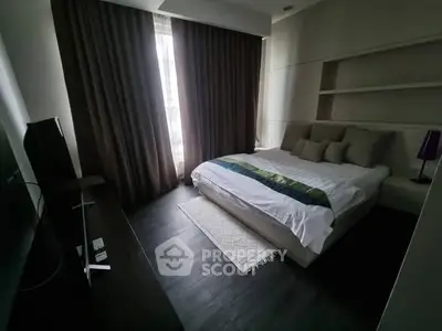 Modern bedroom with cozy bed, dark wood flooring, and natural light from large window.