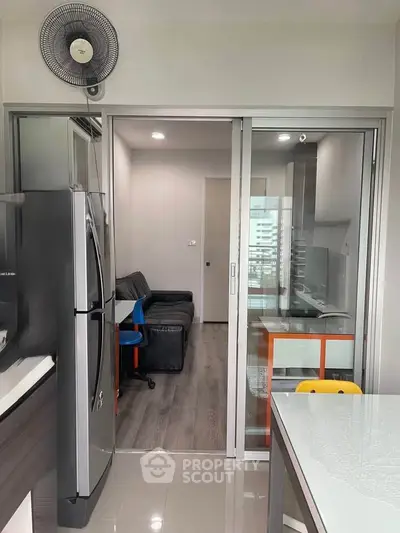 Modern apartment interior with sleek kitchen and cozy living area, featuring sliding glass doors and contemporary furnishings.