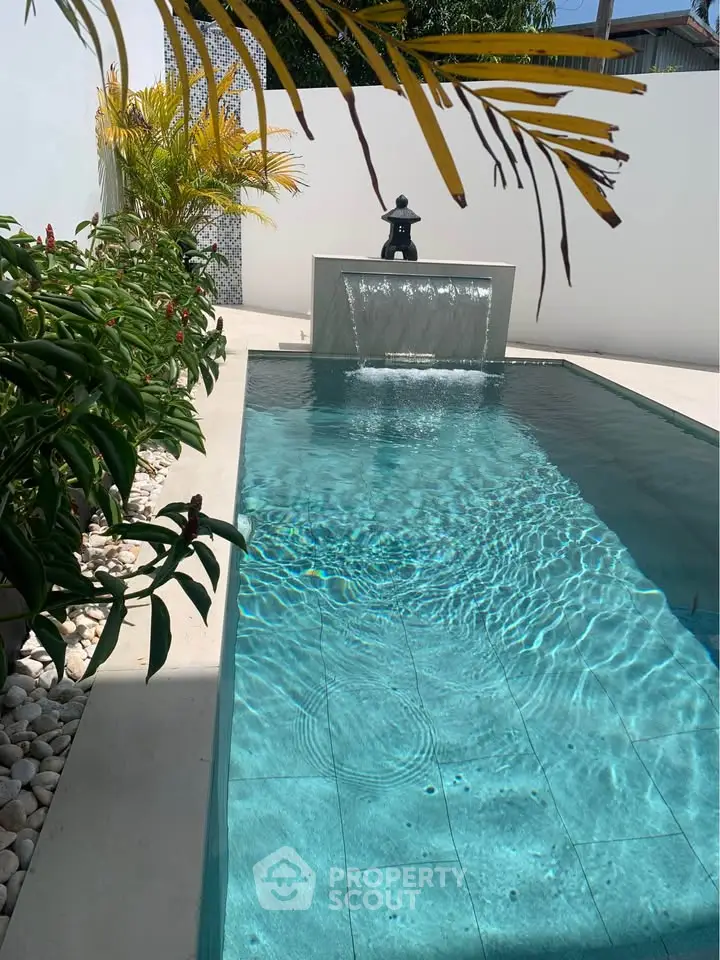 Luxurious private pool with elegant water feature and lush tropical landscaping.