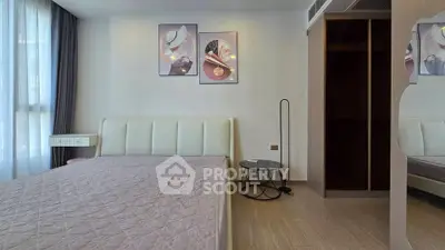 Modern bedroom with stylish decor and ample natural light, featuring a cozy bed and elegant wall art.