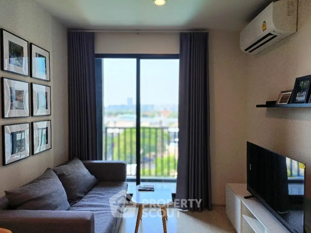Modern living room with large window and city view, featuring a cozy sofa and wall-mounted TV.