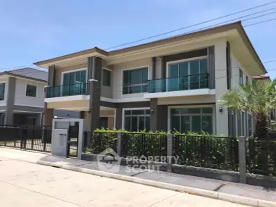 Modern two-story house with large windows and balcony in a suburban neighborhood.