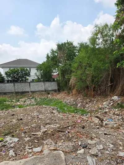 Vacant land plot with potential for development, surrounded by greenery and residential area.