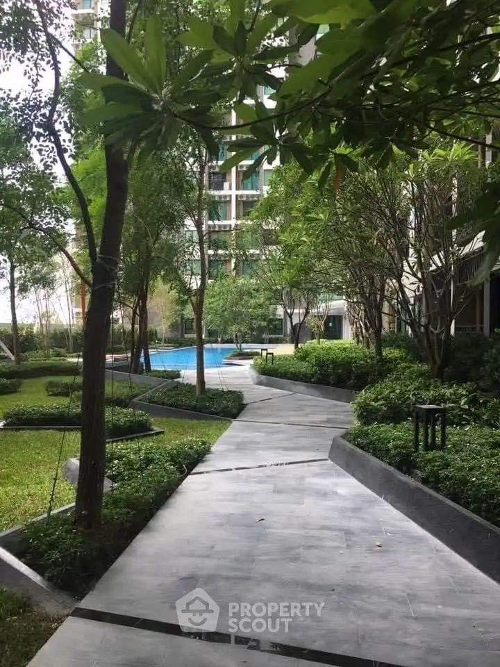 Luxurious garden pathway leading to a serene pool in a modern residential complex.