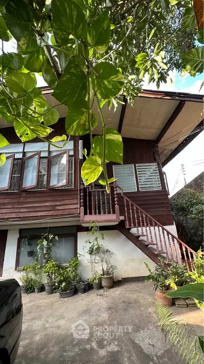 Charming traditional wooden house with lush greenery and outdoor staircase