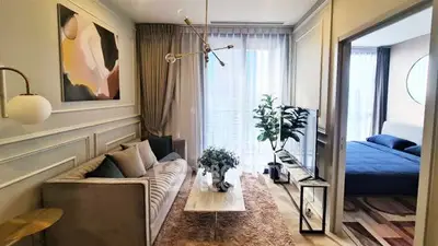 Elegant living room with modern decor and adjacent bedroom, featuring stylish lighting and large windows.