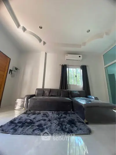 Modern living room with stylish sofa and air conditioning, featuring elegant ceiling design and natural light.
