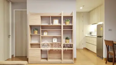Modern living room with stylish wooden shelving and compact kitchen area.