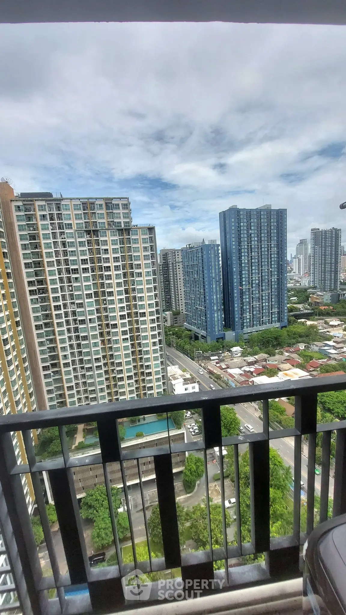 Stunning cityscape view from a high-rise balcony overlooking modern skyscrapers and lush greenery.