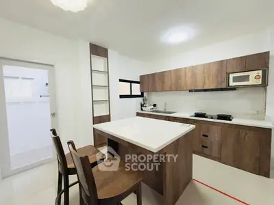 Modern kitchen with wooden cabinets and island, featuring a gas stove and microwave.