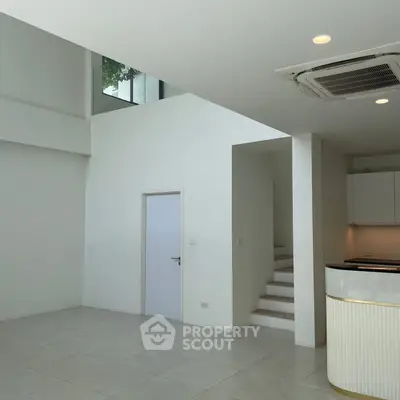 Spacious modern interior with high ceilings and sleek design, featuring a staircase and air conditioning unit.