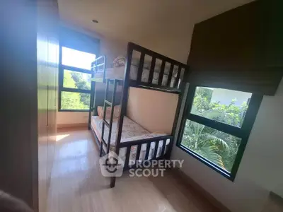 Cozy bedroom with bunk beds and large windows offering lush green views.