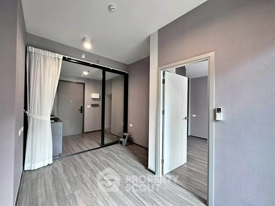 Modern apartment interior with sleek flooring and glass partition, showcasing minimalist design.