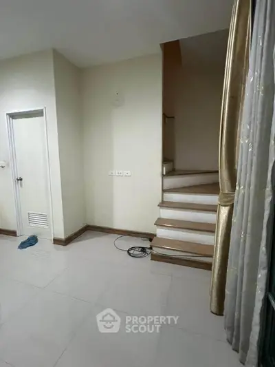 Spacious interior with staircase and elegant curtains, ideal for modern living.