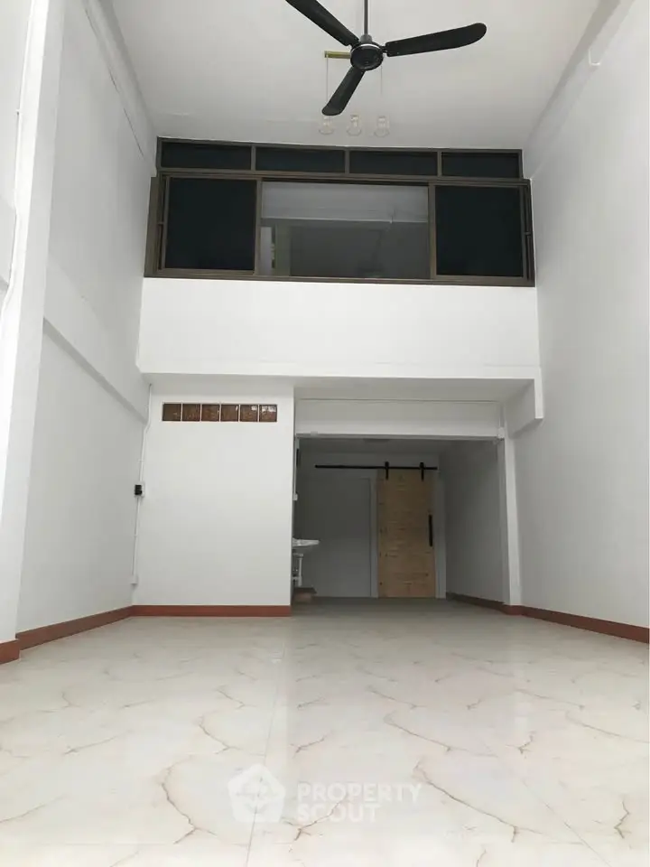 Spacious interior with high ceiling and modern fan, ideal for versatile living space.
