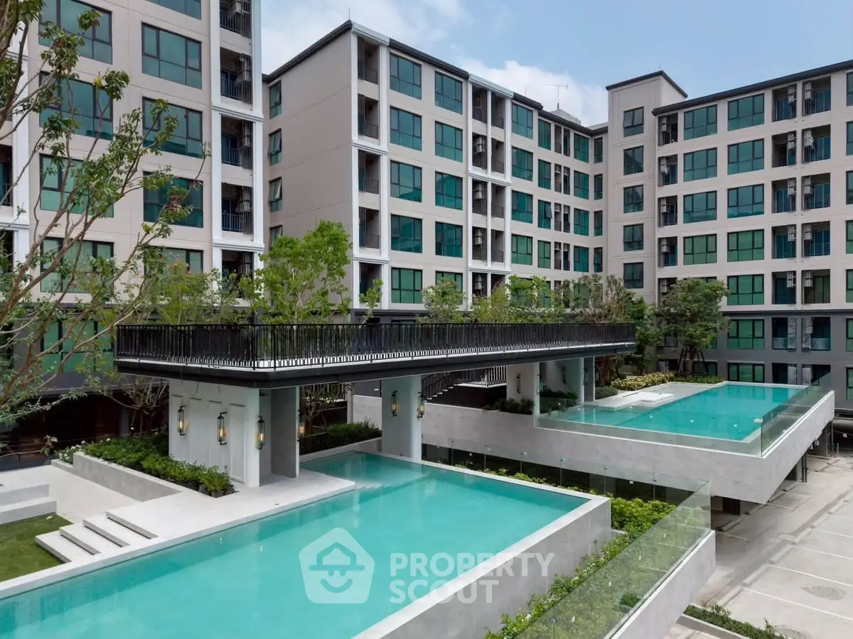 Modern apartment complex with two luxurious swimming pools and lush greenery.