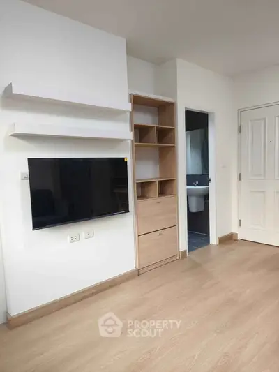Modern living room with wall-mounted TV and built-in storage in a minimalist apartment.