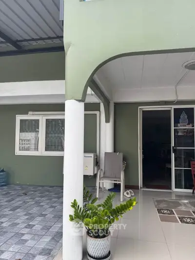 Charming residential entrance with covered patio and potted plant, ideal for relaxation.