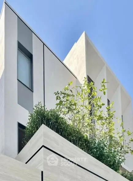 Modern architectural building with sleek design and lush greenery on balcony.