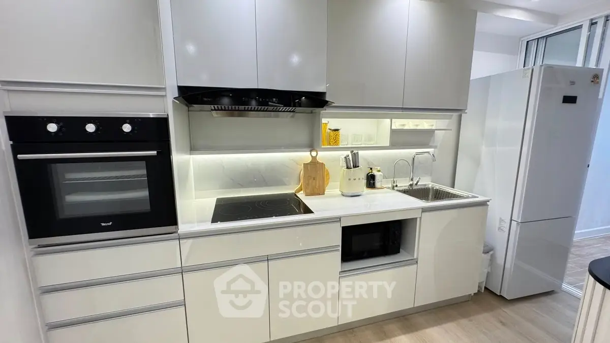 Modern kitchen with sleek cabinetry, built-in oven, and spacious fridge, perfect for culinary enthusiasts.