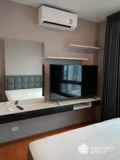 Modern bedroom with wall-mounted TV and air conditioning unit