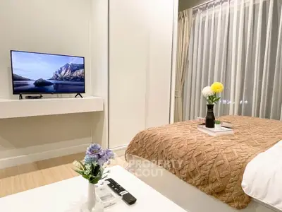 Cozy bedroom with modern decor and a mounted TV, perfect for relaxation.