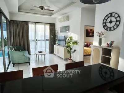 Spacious living room with modern decor and pool view, featuring large windows and stylish furniture.
