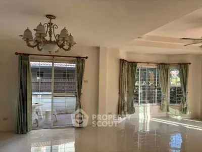 Spacious living room with elegant chandelier and large windows for natural light.