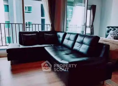 Stylish living room with modern black leather sofa and large windows offering natural light.