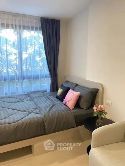 Cozy bedroom with modern decor and large window offering natural light