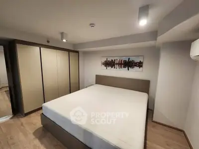 Spacious modern bedroom with large bed and stylish wardrobe in a contemporary apartment.