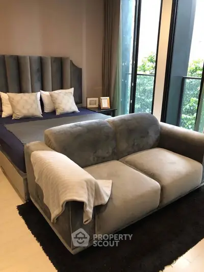 Luxurious bedroom with plush gray sofa and large windows offering a serene view.