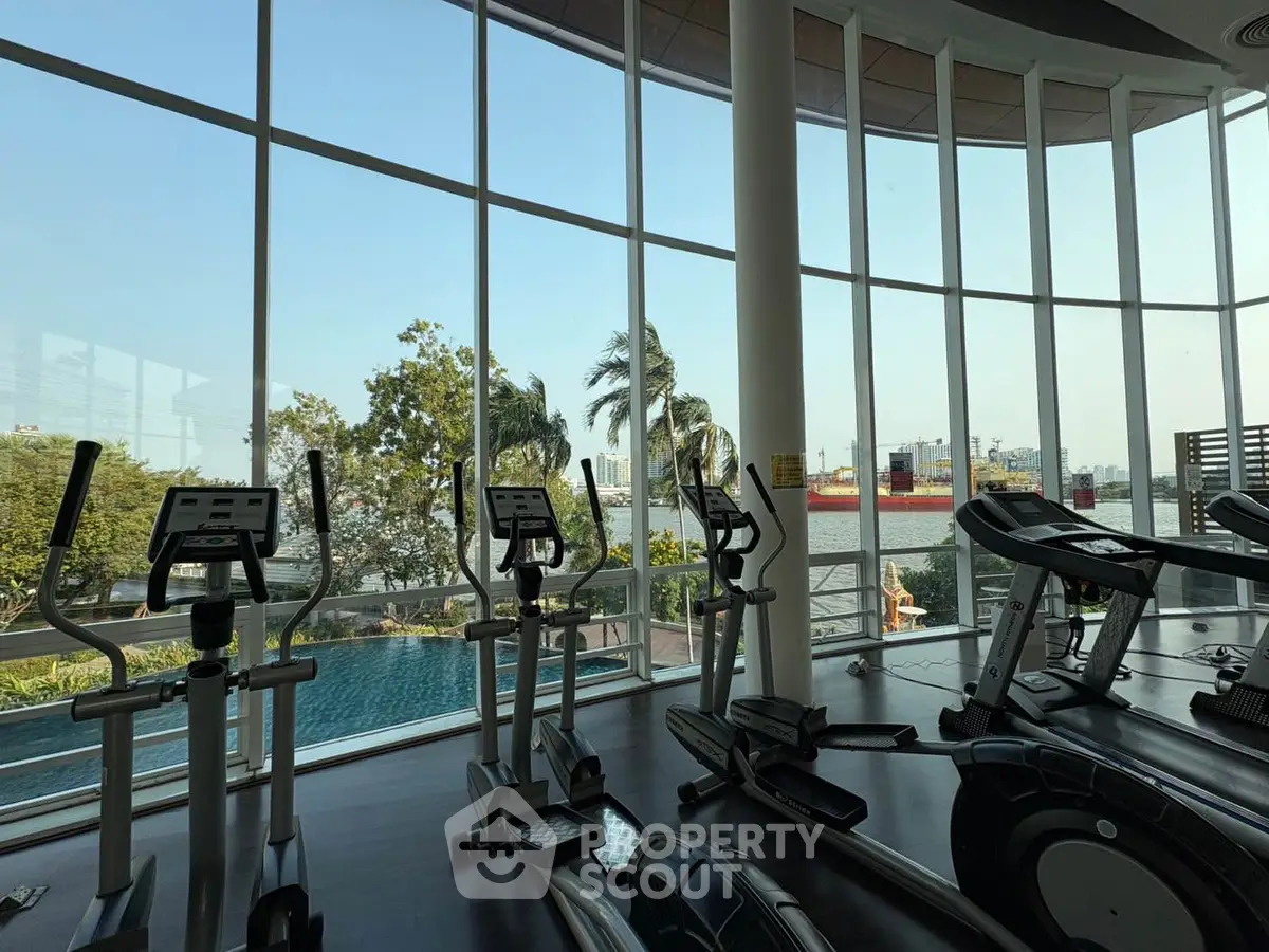 Luxurious gym with panoramic windows overlooking a serene pool and lush greenery.