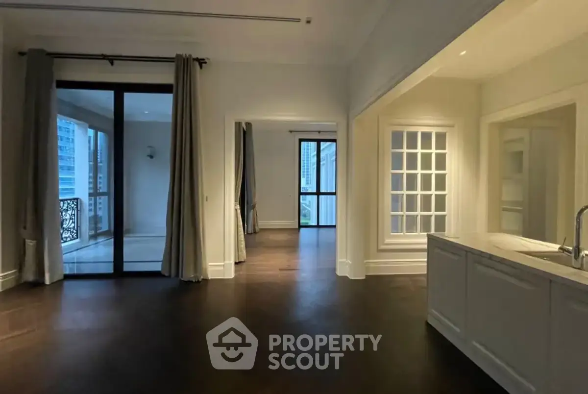 Spacious open-plan living area with elegant dark wood flooring and large windows leading to a balcony.