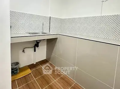 Modern kitchen with sleek tile design and stainless steel sink, perfect for compact spaces.