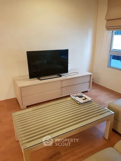 Modern living room with sleek TV setup and stylish coffee table, perfect for relaxation.
