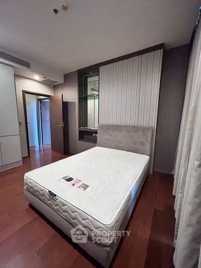 Modern bedroom with hardwood floors and stylish headboard in a cozy apartment.