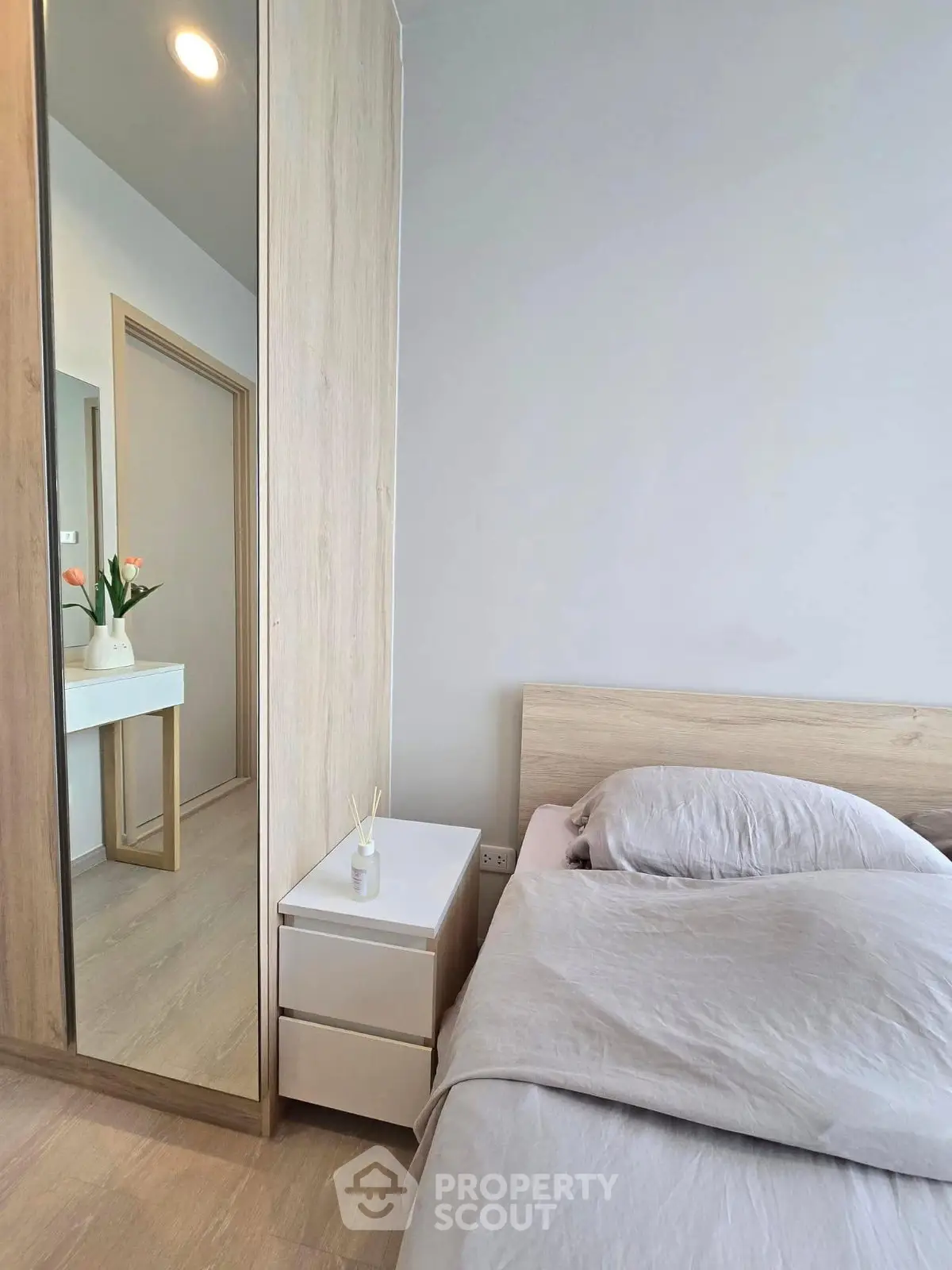 Modern bedroom with wooden accents and mirrored wardrobe in stylish apartment.