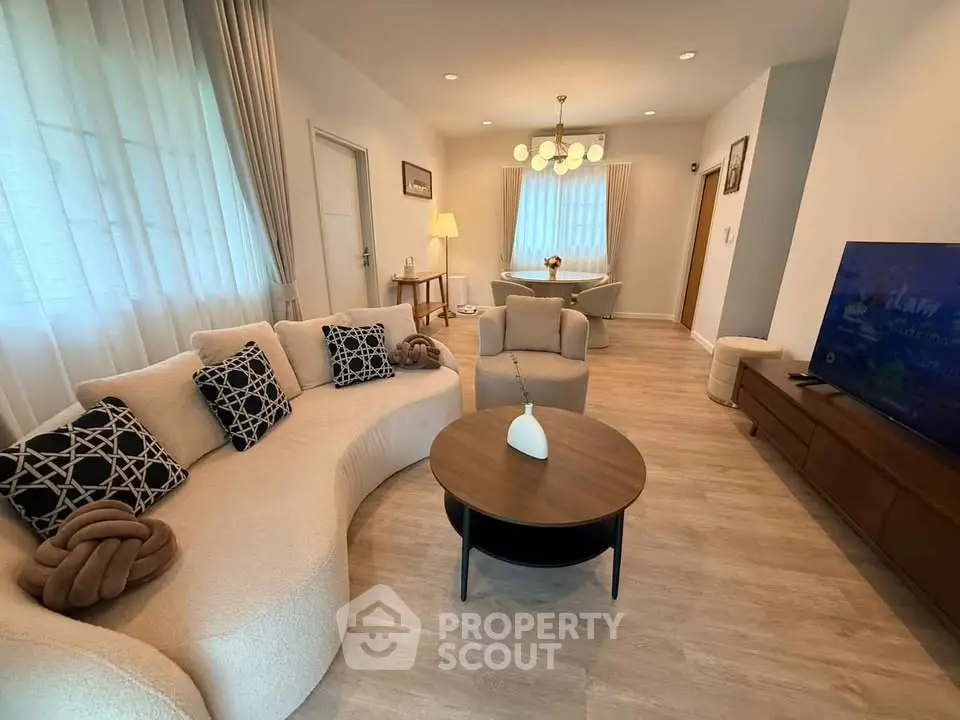 Elegant living room with modern furniture and stylish decor, featuring a cozy seating area and a flat-screen TV.