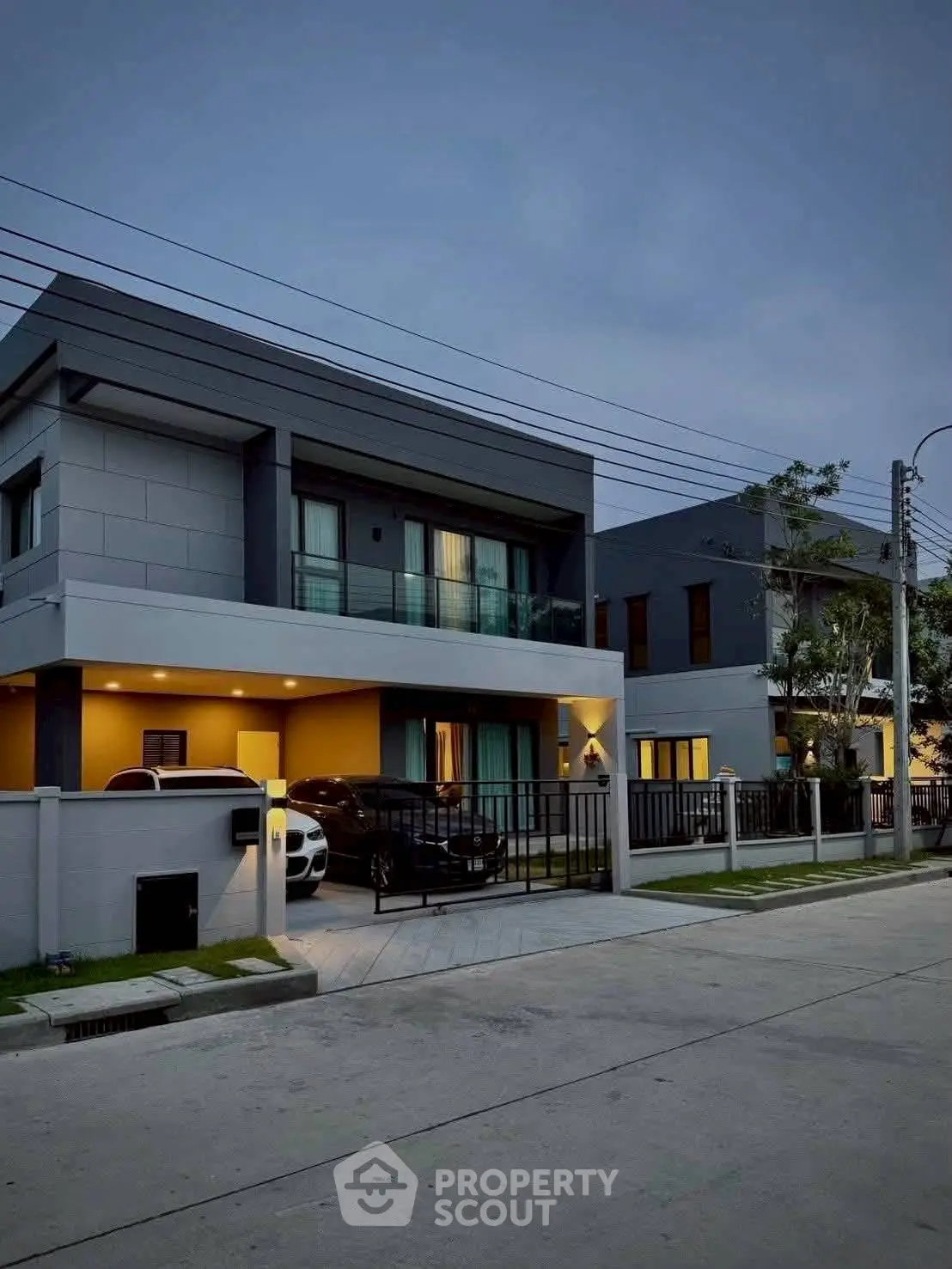 Modern two-story house with sleek design and spacious driveway at dusk.